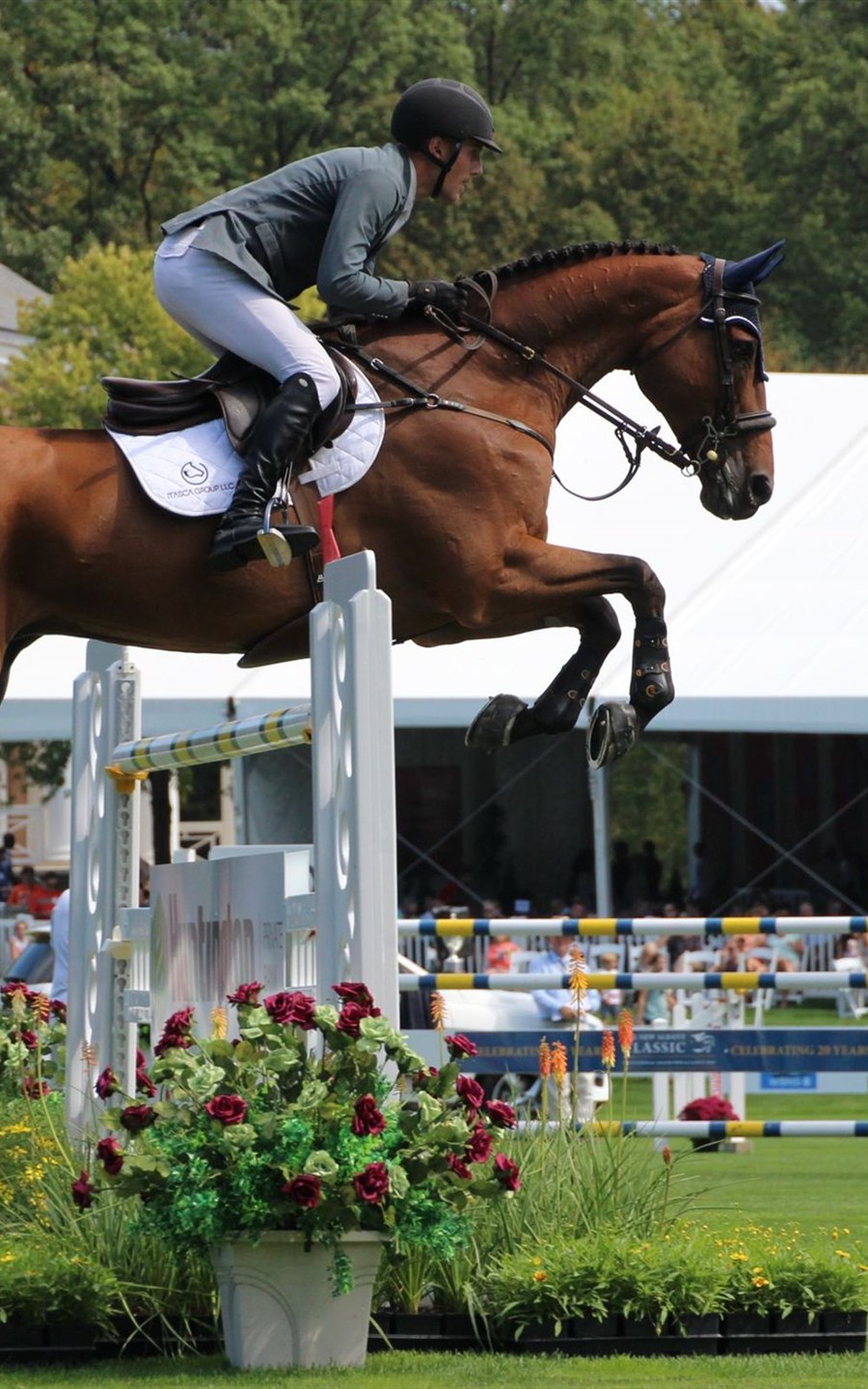 Show jumper clearing an oxer at a competition